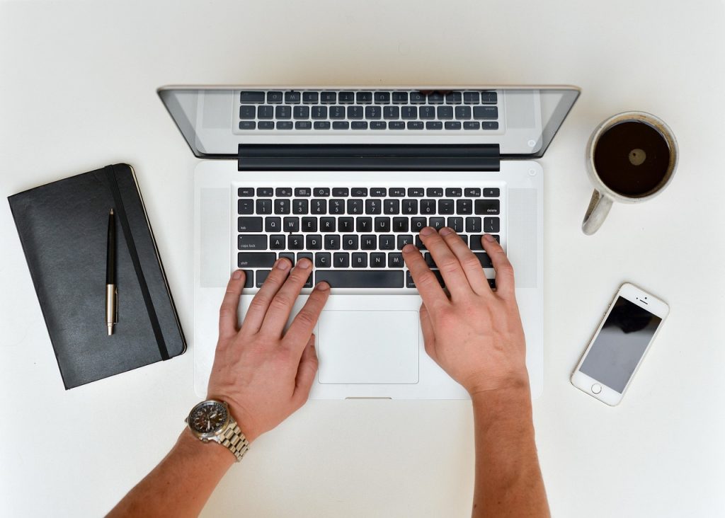 Person stellt einem KI-Assistenten am Laptop eine Frage, beim Morgenkaffee.